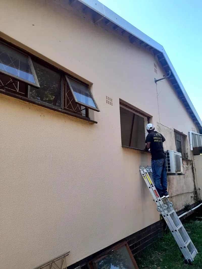Installer on a ladder fitting top-hung windows on a commercial building